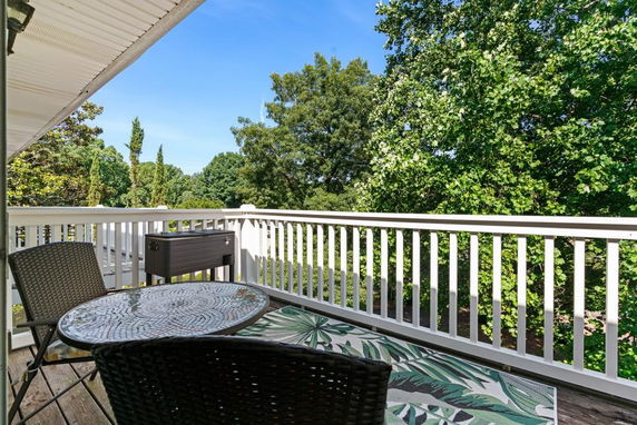 Outdoor patio area with chairs and a table overlooking trees and greenery.