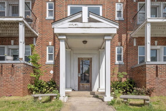 Front view of a brick building with white columns and multiple balconies.