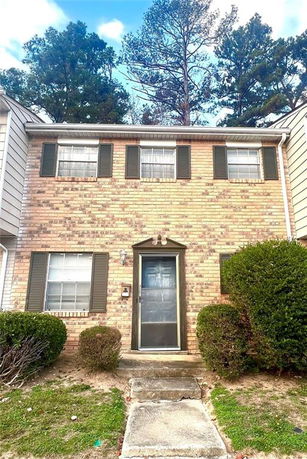 Front view of a two-story brick townhouse with a central entrance and windows.