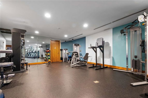 Room with gym equipment including weights and exercise machines.