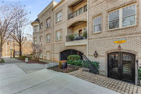 Front view of a multi-story brick building with balconies and a gated entrance.