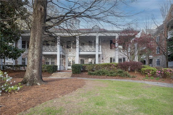 Front view of a two-story house with a balcony and brick exterior.