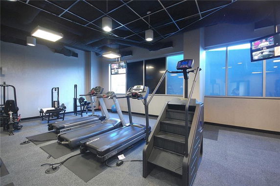 Interior view of a gym with various exercise machines including treadmills and a stair climber.