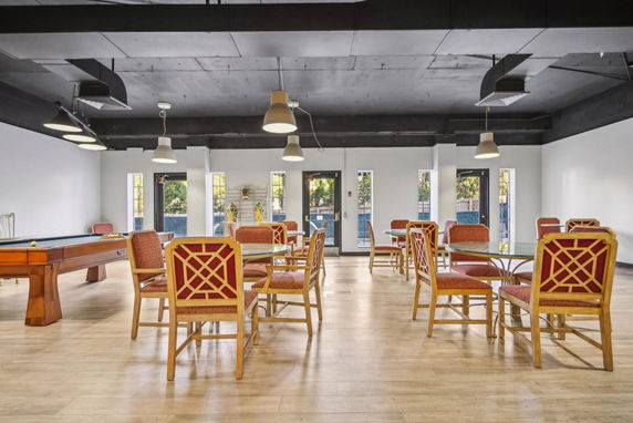 Interior of a clubhouse with tables, chairs, and a billiards table.