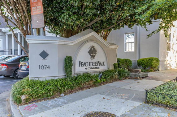 Front view of a condominium entrance with a sign displaying 'Peachtree Walk Condominium'.