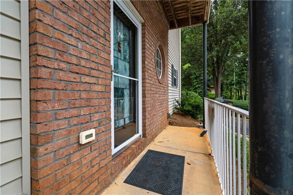 Front view of a brick house with a porch and railing.