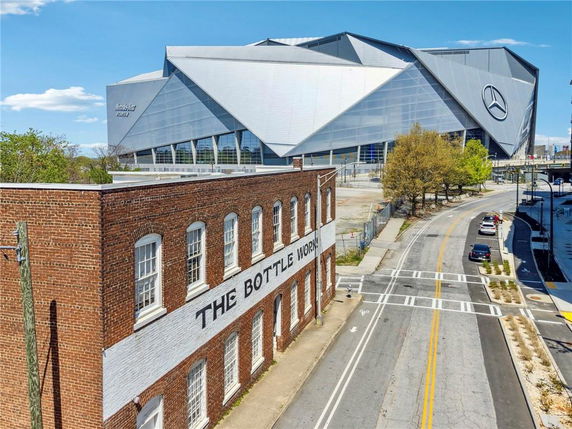Front view of a brick building next to a large modern stadium.
