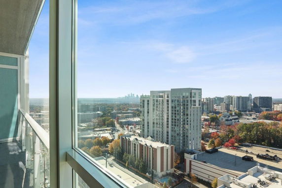 Panoramic view of a cityscape from a high-rise building with glass balcony.