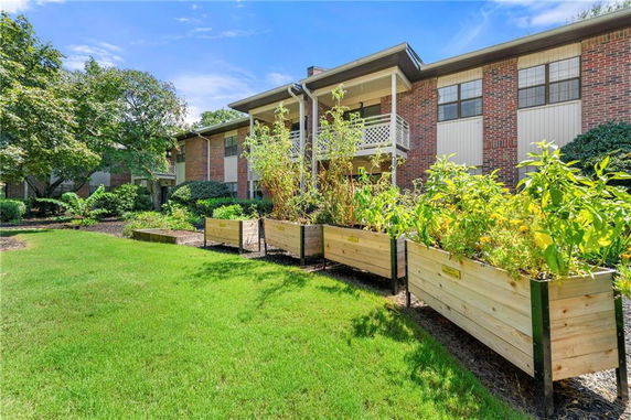 Front view of a two-story brick building with plants in wooden planters.