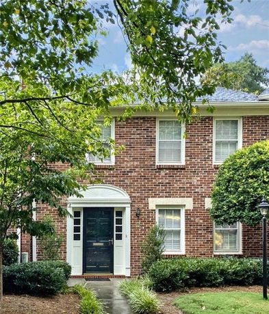 Front view of a two-story brick house with a central doorway and white-trimmed windows.