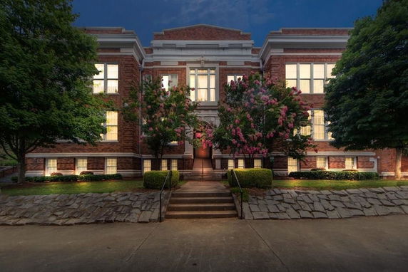 Front view of a multi-story brick building with large windows and a central entrance staircase.