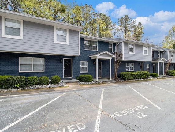 Front view of a two-story residential building with multiple entrances and reserved parking spaces.