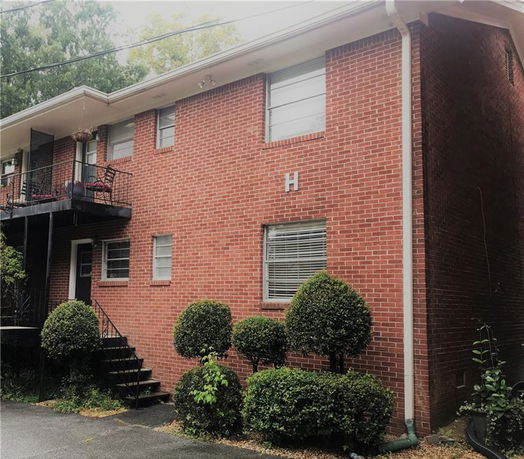 Front view of a two-story brick building with a balcony and stairs.