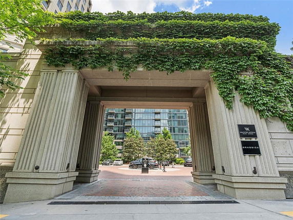 Front view of a building entrance with pillars and greenery on top.