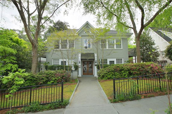 Front view of a two-story house with a pathway and surrounding greenery.