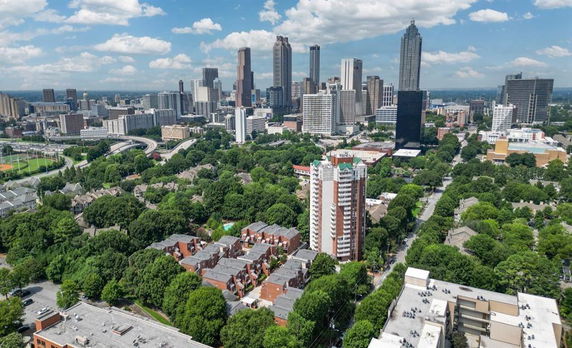 Panoramic view of a city skyline with tall buildings and lush greenery.