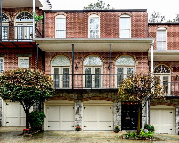 Front view of a multi-story brick building with a double garage and balcony.
