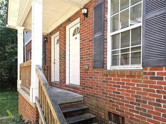 Front view of a brick house with a small porch and white doors.