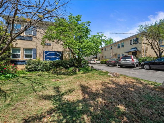Front view of a two-story condominium building complex with a driveway and parked cars.