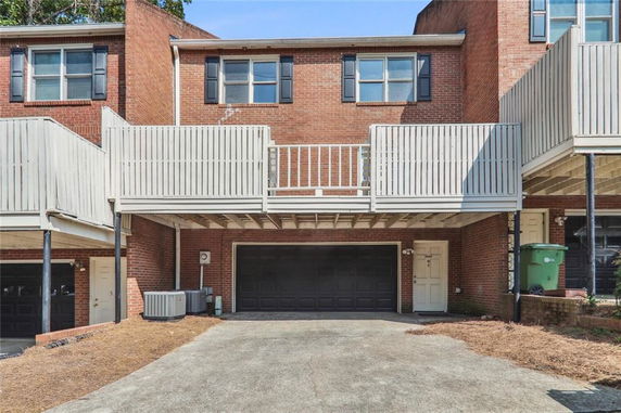 Front view of a brick two-story townhouse with a balcony and garage.