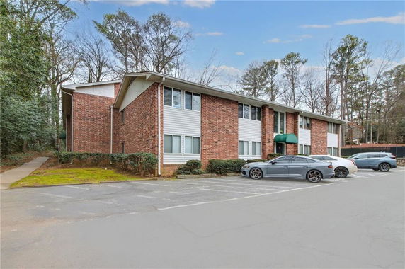 Front view of a two-story brick apartment building with parked cars in front.