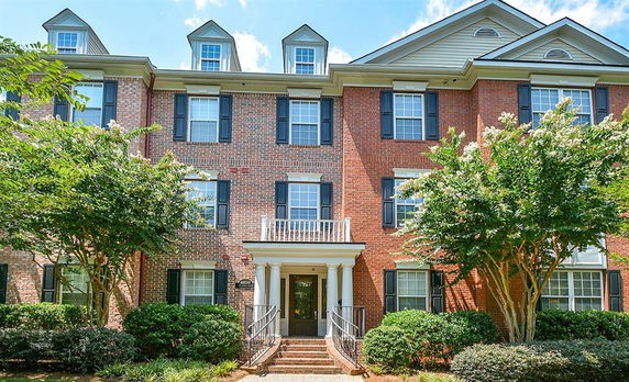 Front view of a multi-story brick residential building with white columns and a central entrance.