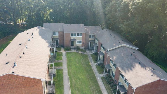 Aerial view of two-story residential buildings with brick exterior, arranged in a U-shape around a central grassy area.