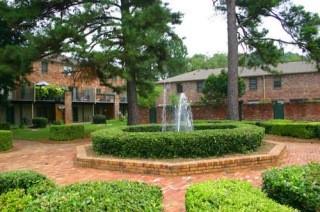 View of apartment buildings with trees and a central fountain.