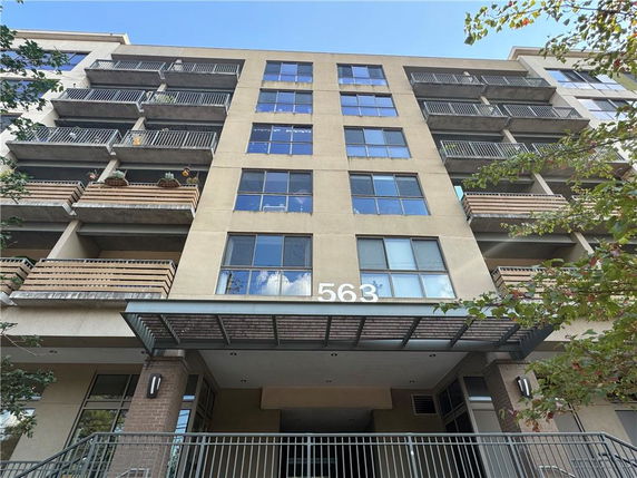 Front view of a multi-story building with balconies and large windows.