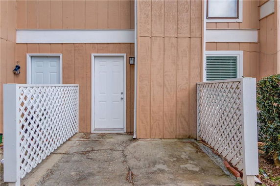 Front view of a house entrance with two doors and lattice fencing.