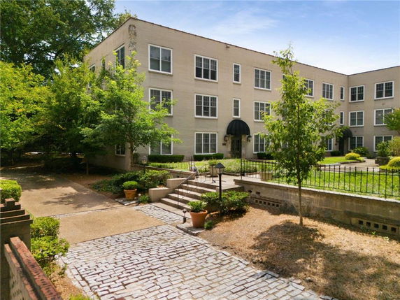 Front view of a multi-story building with multiple windows and a garden area.