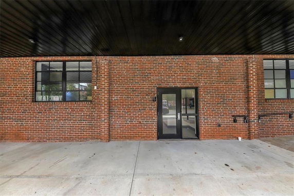 Front view of a brick building with a glass door and windows.