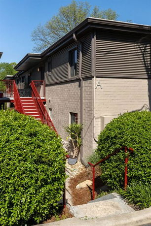Front view of a two-story building with a red staircase and brick exterior.