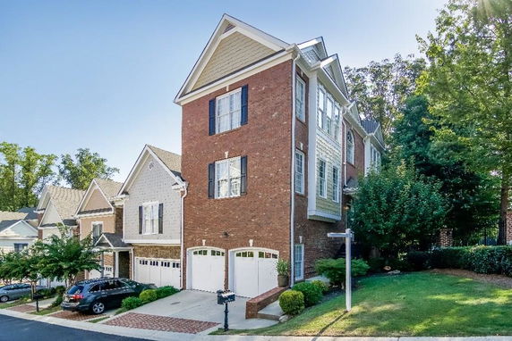 Front view of a multi-story house with a brick facade and double garage.