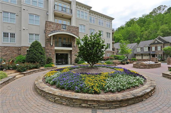 Front view of a multi-story building with stone and stucco exterior and landscaped garden.
