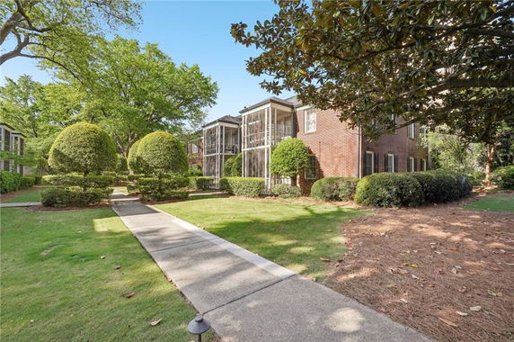 Front view of a brick building with screened porches and neatly trimmed hedges.