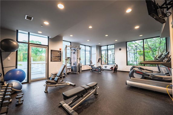 Interior view of a gym with exercise equipment and large windows.