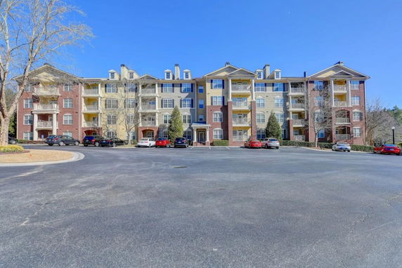 Front view of a multi-story apartment building with parking in front.