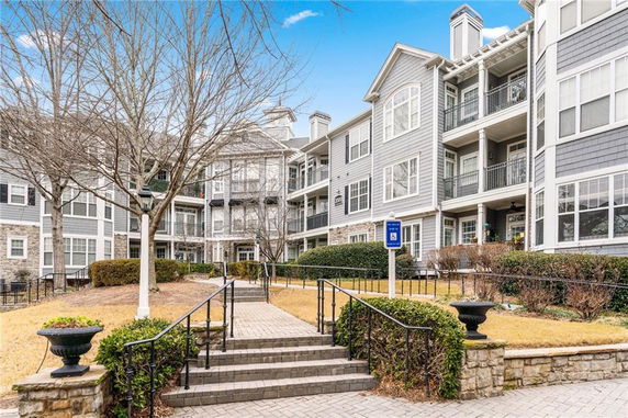 Front view of a multi-story residential building with balconies and stone accents.