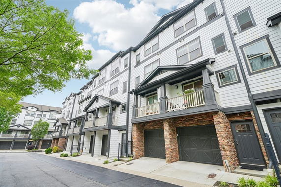 Front view of a multi-story residential building with garage entrances and balconies.