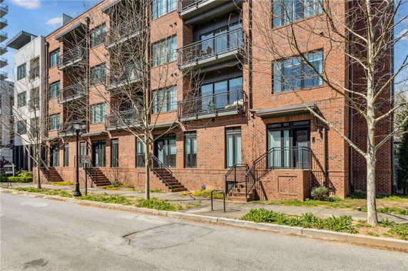 Front view of a multi-story brick apartment building with balconies.