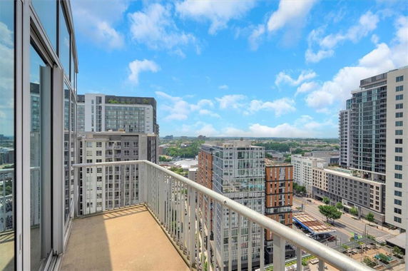 View from a balcony overlooking a cityscape with multiple high-rise buildings.