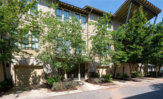 Front view of a multi-story residential building with large windows and a garage.
