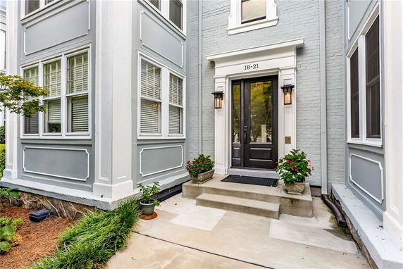 Front view of a building entrance with black double doors and decorative plants on either side.