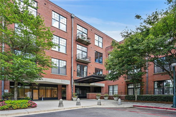 Front view of a multi-story brick apartment building with large windows and balconies.