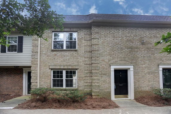 Front view of a two-story brick townhouse with dark doors and windows.