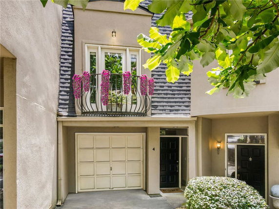 Front view of a house with a garage and a small balcony adorned with flowers.