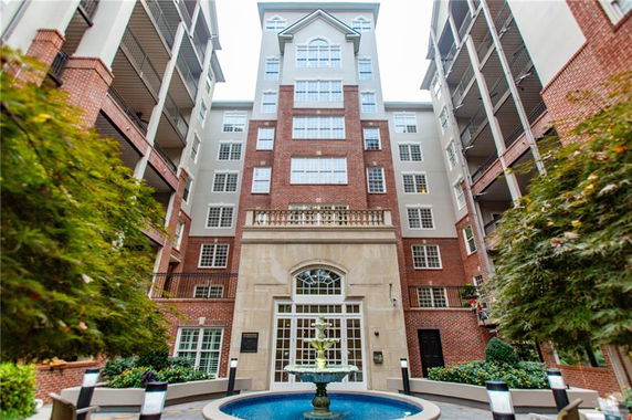 Front view of a multi-story residential building with a brick facade and balconies.