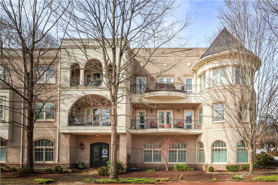 Front view of a three-story brick building with balconies and arched windows.