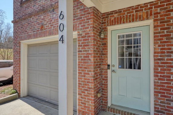 Front view of a house entrance with a garage and brick exterior.